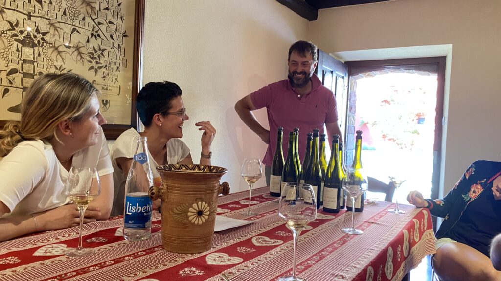 fröhliche Gäste am Tisch eines Winzers bei einer Weindegustation